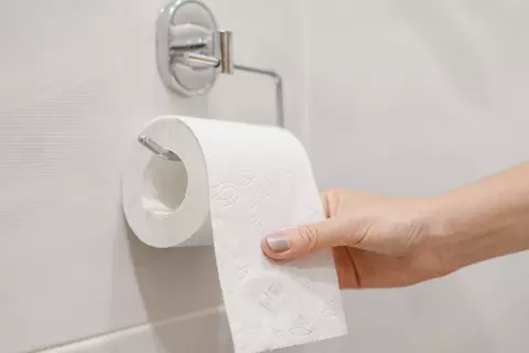 Hand greift an Toilettenpapierrolle