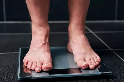Nackte Füße eines Mannes auf Körperwaage