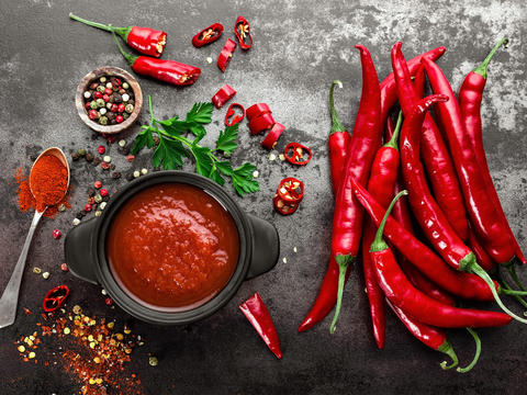 Ganze, rote Chili-Schoten und Schüssel mit Chili-Soße