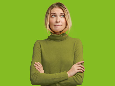 Frau mit verschränkten Armen schaut etwas gequält