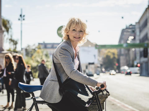 Frau schiebt Fahrrad im Straßenverkehr
